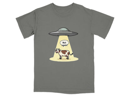 Funny t-shirt design featuring a cow being abducted by aliens with the text 'Not again!'