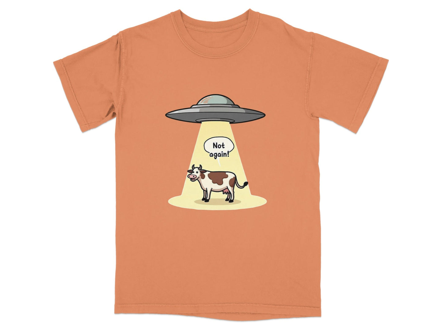 Funny alien abduction cartoon t-shirt with cow and 'Not again!' speech bubble on orange background.