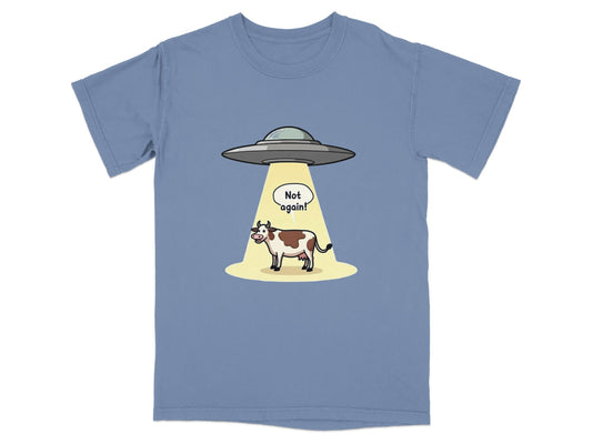 Funny t-shirt design featuring a cow being abducted by aliens with the text 'Not again!' in a cartoon style.
